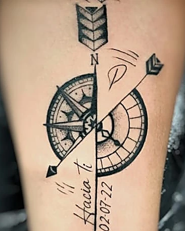 Brújula partida por una flecha, con fecha y letras, en el antebrazo