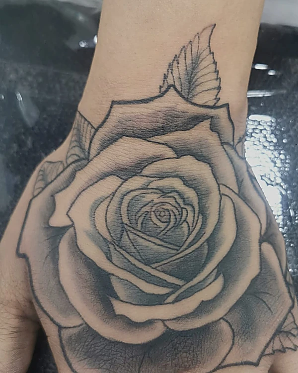 Rosa grande en realismo negro y gris sobre el dorso de la mano